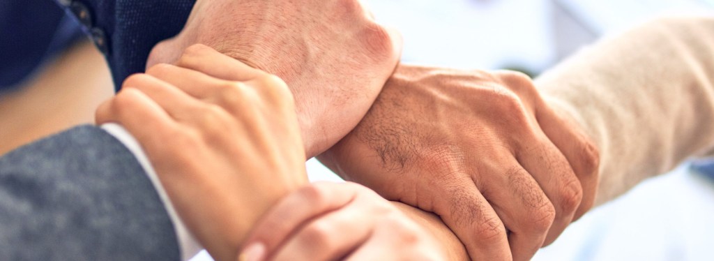 Four hands interlocking at the wrist